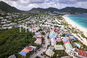 An aerial view of a coastal town with a beach, houses, and lush greenery. - Very nice 2 bed-rooms apartment at Orient Beach (Collectivité de Saint-Martin)
