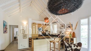 A spacious kitchen with a central island, wooden bar stools, and a hanging light fixture.