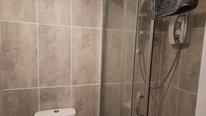 Ett badrum med en dusch som är avskärmad med glasväggar, en toalett och en handduksställning.