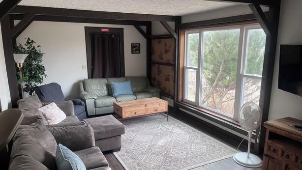 Una sala de estar acogedora con un sofá modular, una mesa de centro de madera y un ventanal con vistas a árboles.