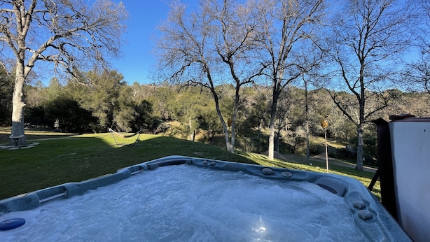 Un bain à remous dans un parc, entouré d’arbres et bordé d’une pelouse.