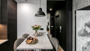 Un'area pranzo moderna con un tavolo lungo, sedie, una lampada a sospensione e un vaso con fiori.