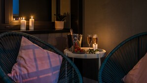 Un'accogliente zona con sedute in vimini, un tavolino, candele e una bottiglia di champagne.