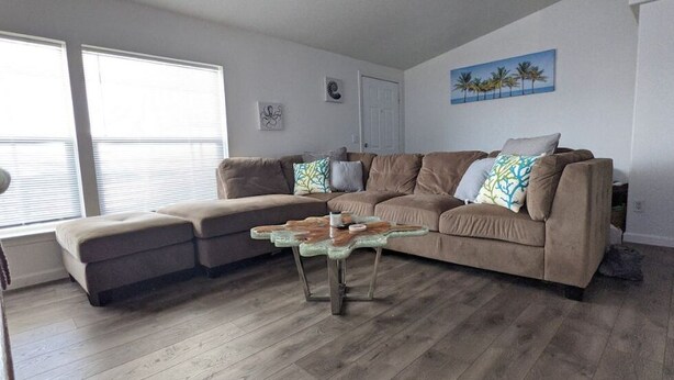 A living room with a brown sectional sofa, a glass coffee table, and a wooden floor. - Parker, AZ - Hilltop Hideaway (Parker)