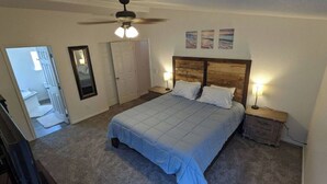 A bedroom with a bed, bedside tables, a ceiling fan, and a door leading to another room. - Parker, AZ - Hilltop Hideaway (Parker)