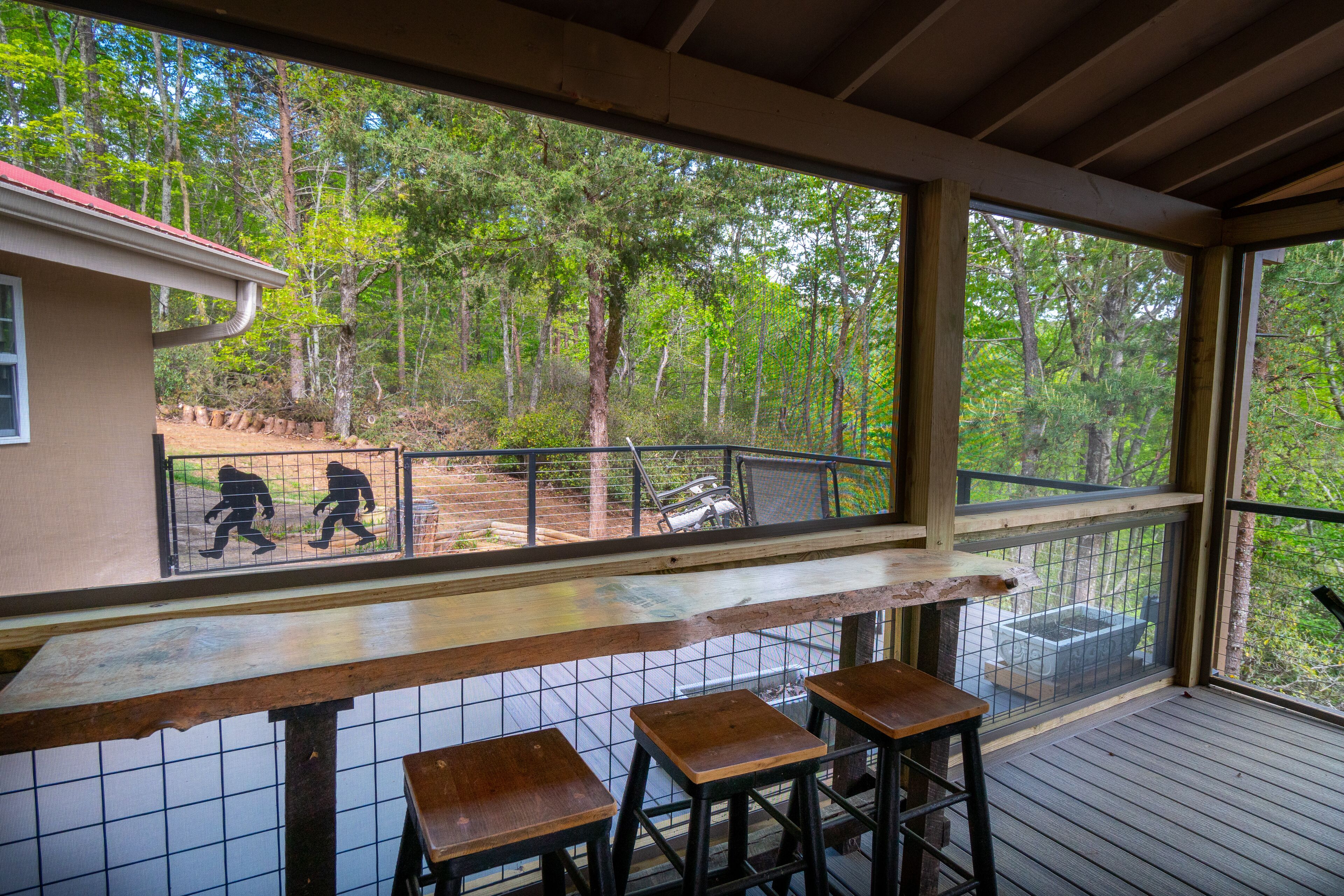 A covered outdoor seating area with a view of a forested area.