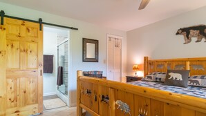 Une chambre avec un lit en bois, une porte coulissante, un miroir et un coussin à motifs d’ours.