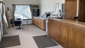 A compact kitchen with a wooden counter, a microwave, a sink, and a small dining area with a table and chairs.