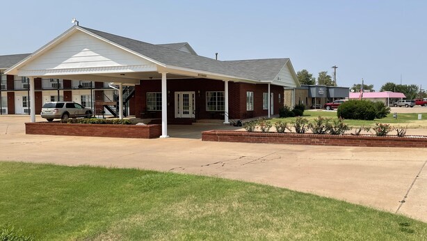 A two-story motel with a covered front porch, a brick facade, and a parking lot.