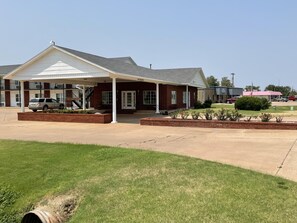 A two-story motel with a covered front porch, a brick facade, and a parking lot. - Heritage Inn (Fairview)