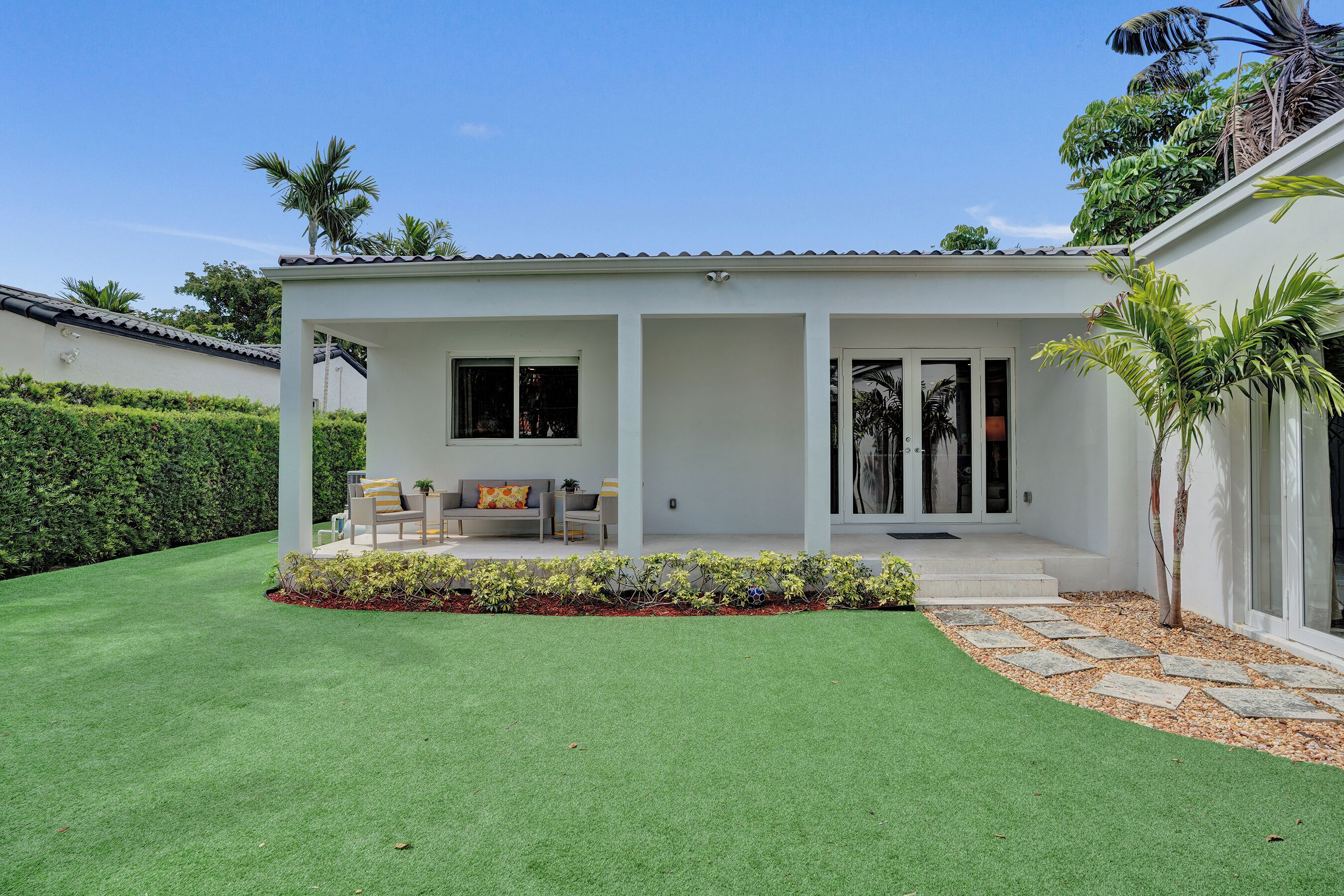 Ein modernes Haus mit Terrasse, Rasen und Garten.