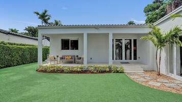 Ein modernes Haus mit Terrasse, Rasen und Garten.