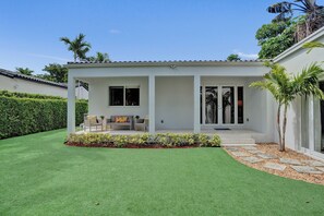 Ein modernes Haus mit Terrasse, Rasen und Garten.