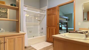 A bathroom with a bathtub, a sink, wooden cabinets, and a shower area.