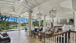 A spacious indoor area with a high ceiling, large windows, and a view of a landscaped garden. - Breathtaking Oceanfront Resort, 4 pools, 2 Jacuzzis and Restaurants on Site  (Lihue)