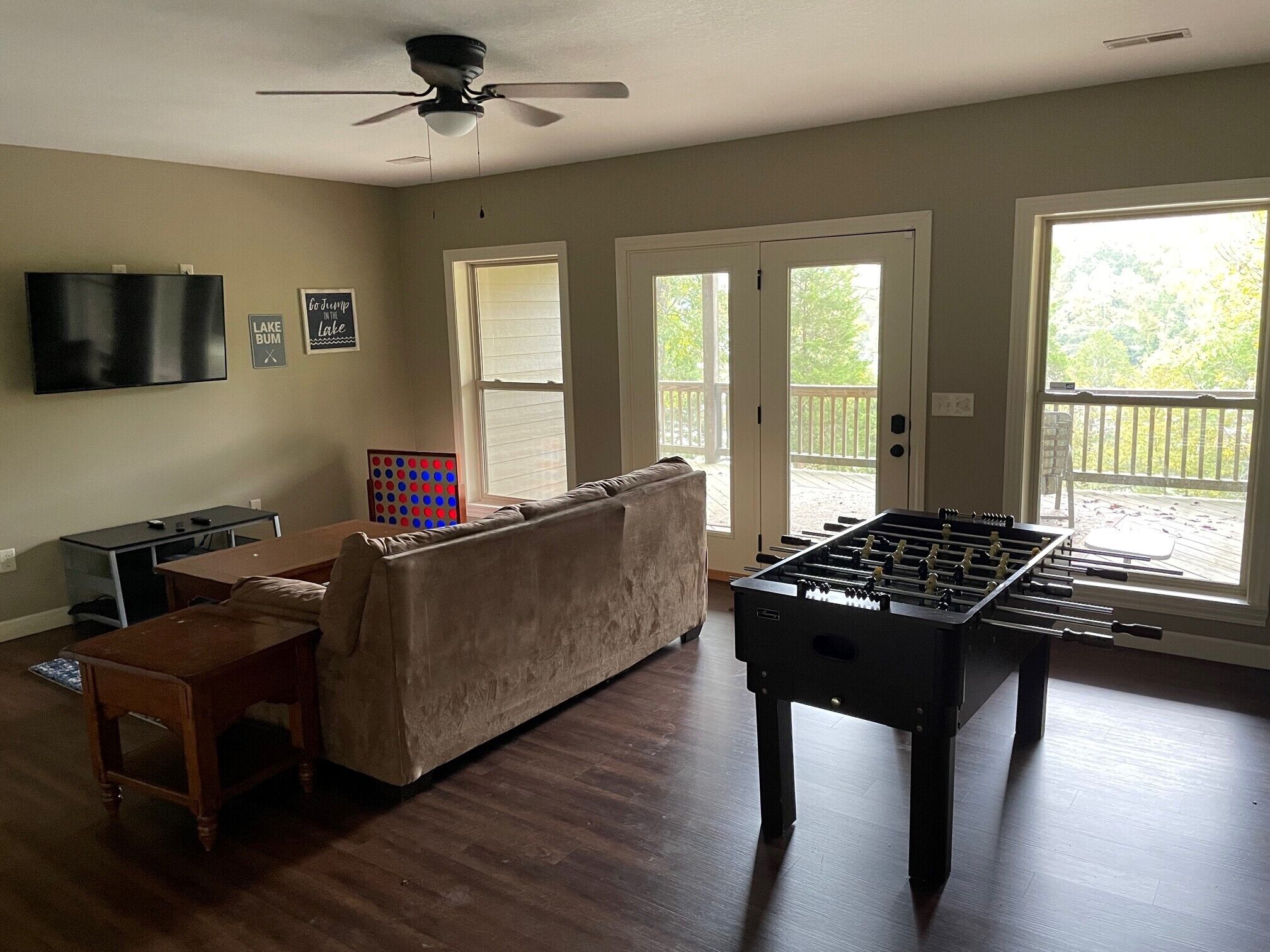 A living room with a foosball table, a sofa, a TV, and a table with a board game.
