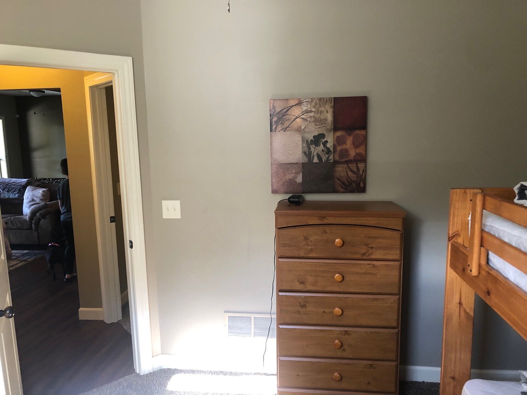 Une pièce comprenant une commode en bois, un lit superposé et une œuvre d’art accrochée au mur.