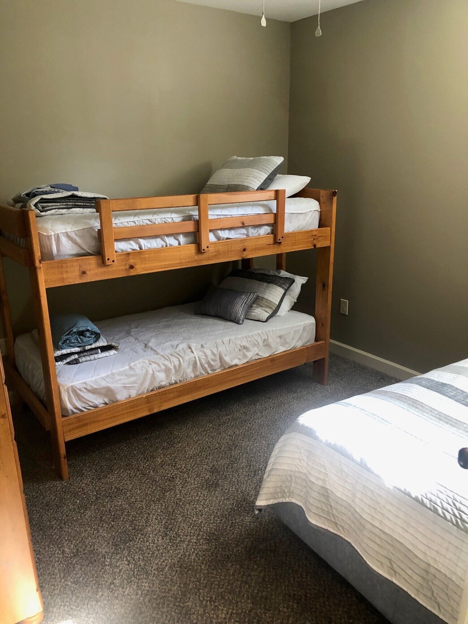 A bunk bed with two levels, a carpeted floor, and a plain wall.