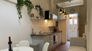 A modern kitchen with white cabinets, a dining area with a white table and chairs, and a cozy seating area with a sofa.