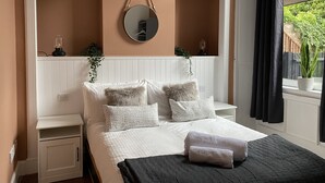 A bedroom with a bed, bedside tables, a mirror, and a window with curtains.
