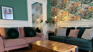 A living room with two sofas, a coffee table, and a floral wallpaper.