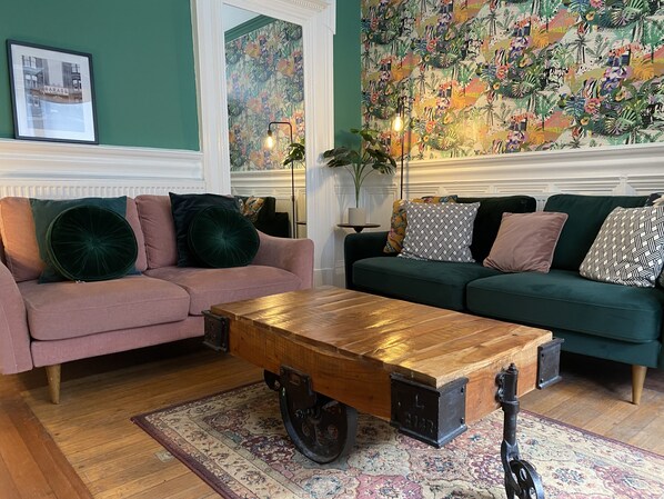 Ein Wohnzimmer mit zwei Sofas, einem Couchtisch und floralem Wandpapier.