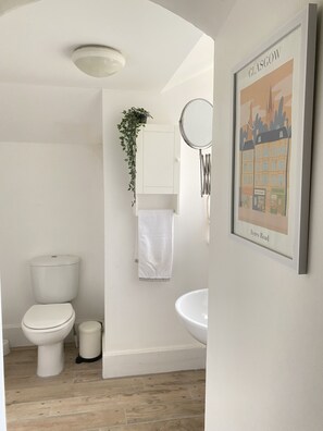Ein modernes Badezimmer mit Toilette, Waschbecken und einem gerahmten Bild von Glasgow.
