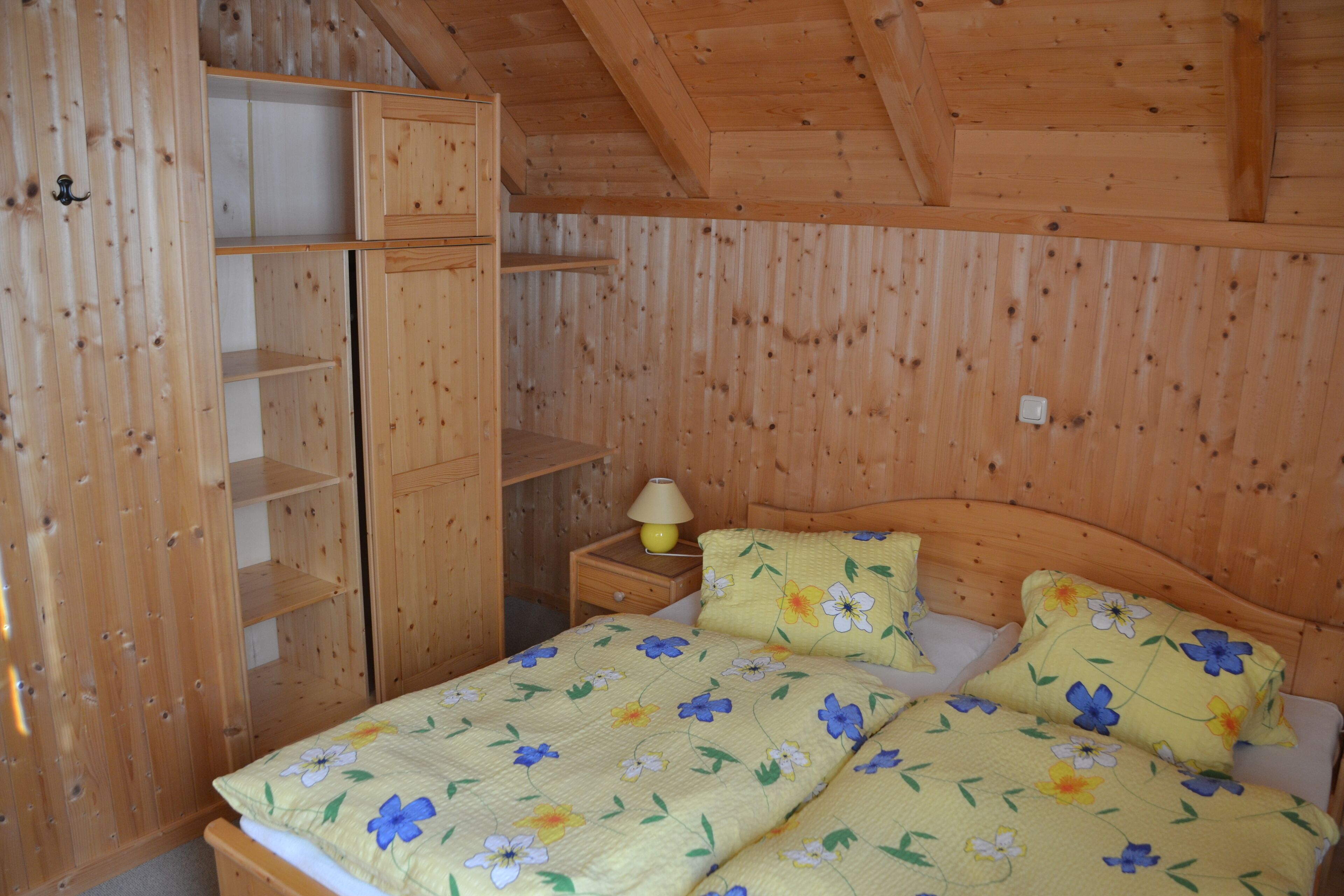 Une chambre à coucher en bois, avec un lit, une table de chevet et une armoire.
