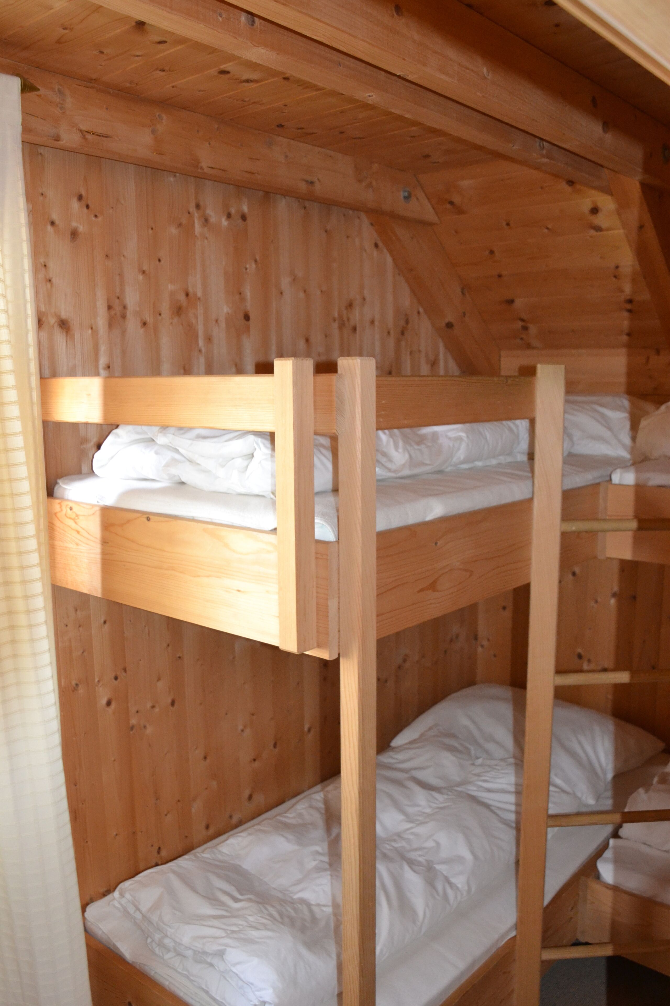 A bunk bed room with wooden walls and a sloped ceiling.