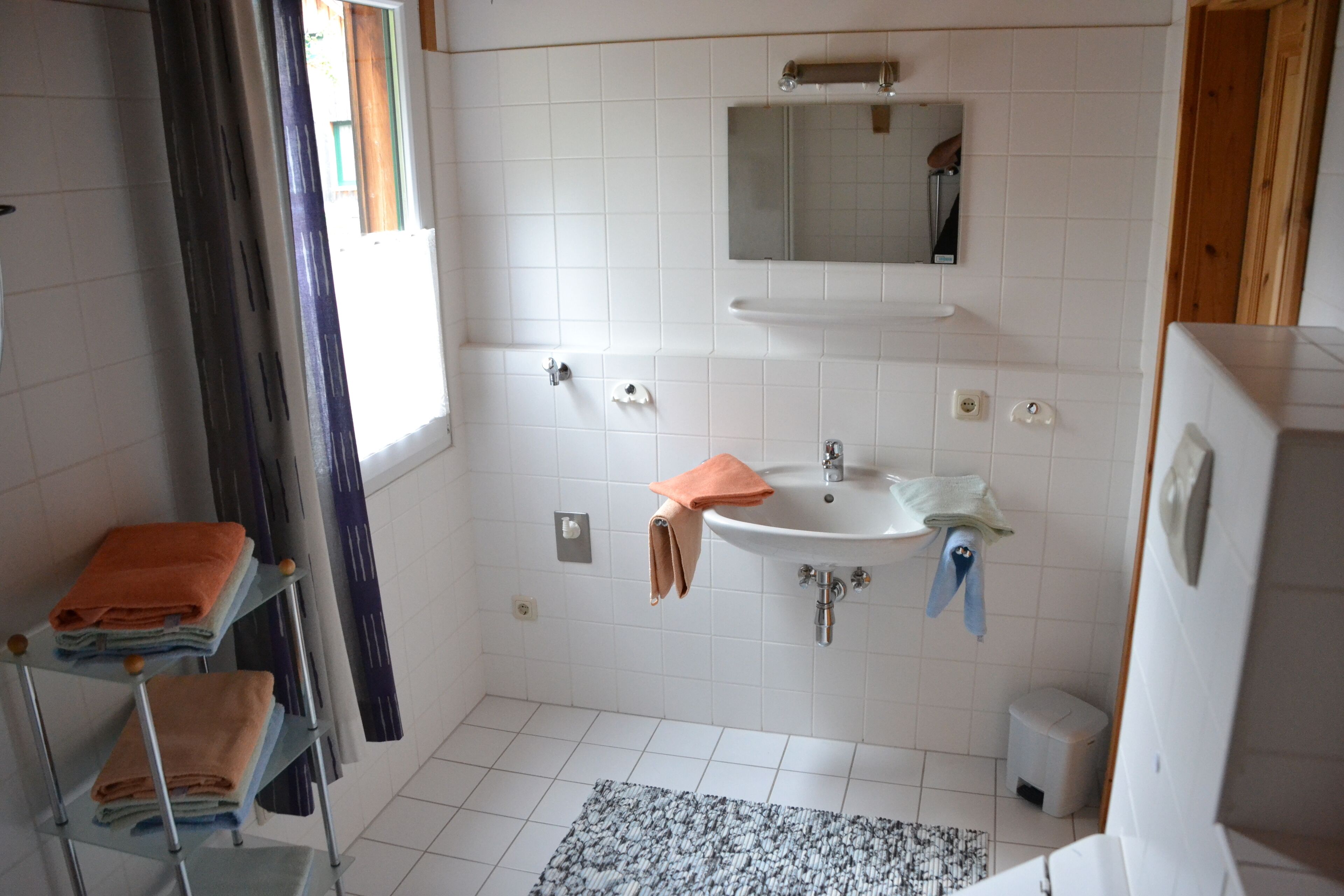 Een bad/douchecombinatie, handdoeken, toiletpapier