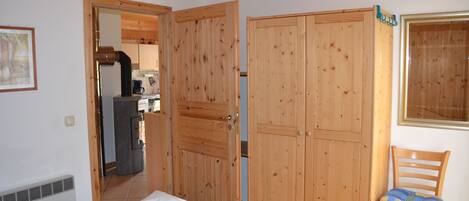 A bedroom with a bed, wooden wardrobe, and a chair.