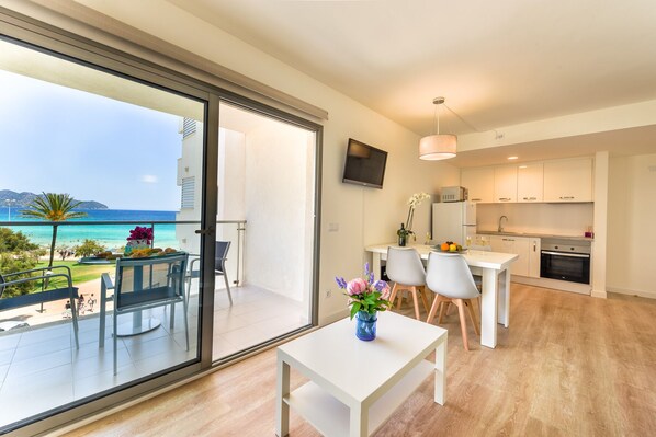 A modern apartment with a balcony overlooking a beach, a dining area, and a kitchen.