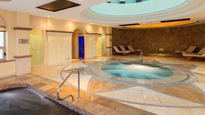A spa area with a hot tub, lounge chairs, and a blue door.