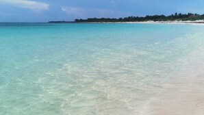Een strand met helder turquoise water en een zandstrand.
