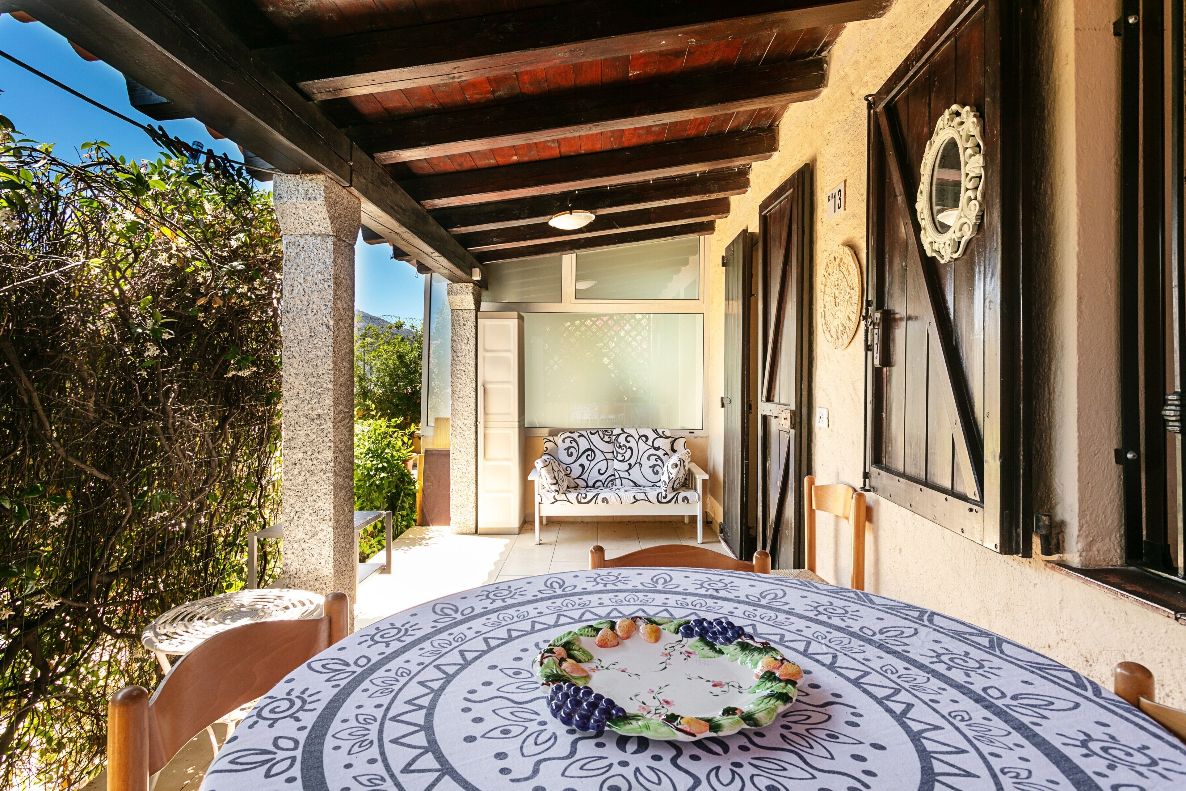 Eine überdachte Terrasse mit Tisch, Stühlen und einer Sitzecke.