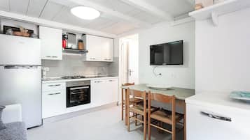 Een koelkast, een oven, een kookplaat, kookgerei, borden en bestek