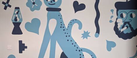 A wall with a blue cat, hearts, and abstract shapes.
