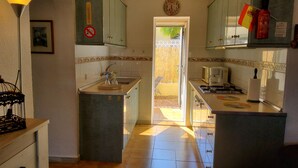Een keuken met een kookplaat, magnetron en een klok aan de muur.