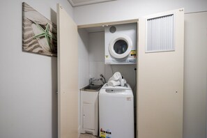 A compact laundry room with a washing machine, a dryer, and a sink.