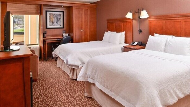 A hotel room with two beds, a desk, a chair, and a television. - McKnight Hotel (Pittsburgh)