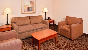 A hotel room with a striped sofa, a wooden coffee table, a cushioned armchair, and a patterned carpet. - McKnight Hotel (Pittsburgh)
