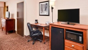 A hotel room with a desk, a chair, a television, a microwave, and a refrigerator. - McKnight Hotel (Pittsburgh)
