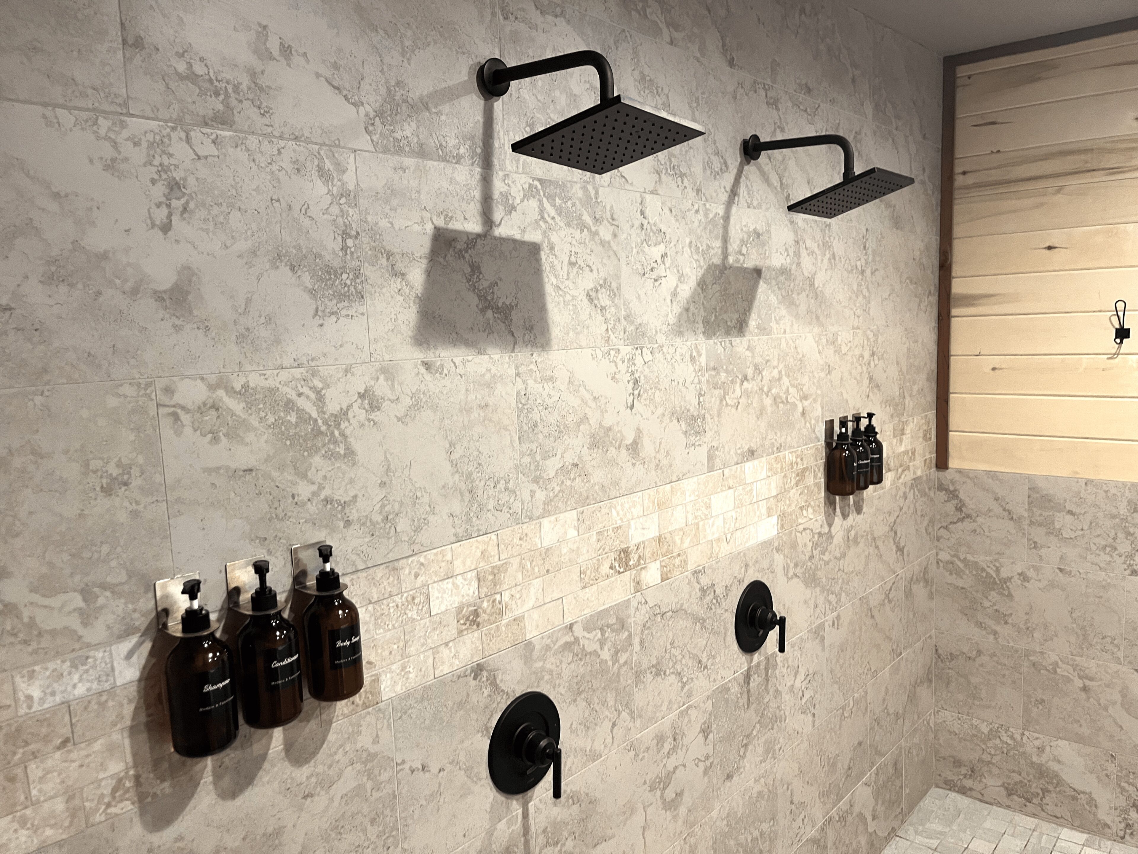 A bathroom with a shower, a towel rack, and a soap dispenser wall.
