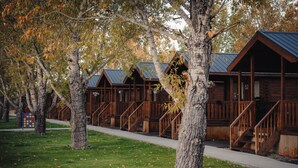 A row of log cabins with wooden railings and stairs leading to the entrance. - Blue Buffalo Resort (Island Park)