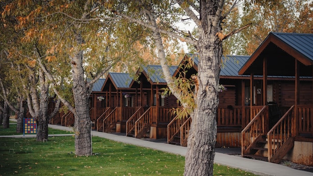 A row of log cabins with wooden railings and stairs leading to the entrance. - Blue Buffalo Resort (Island Park)