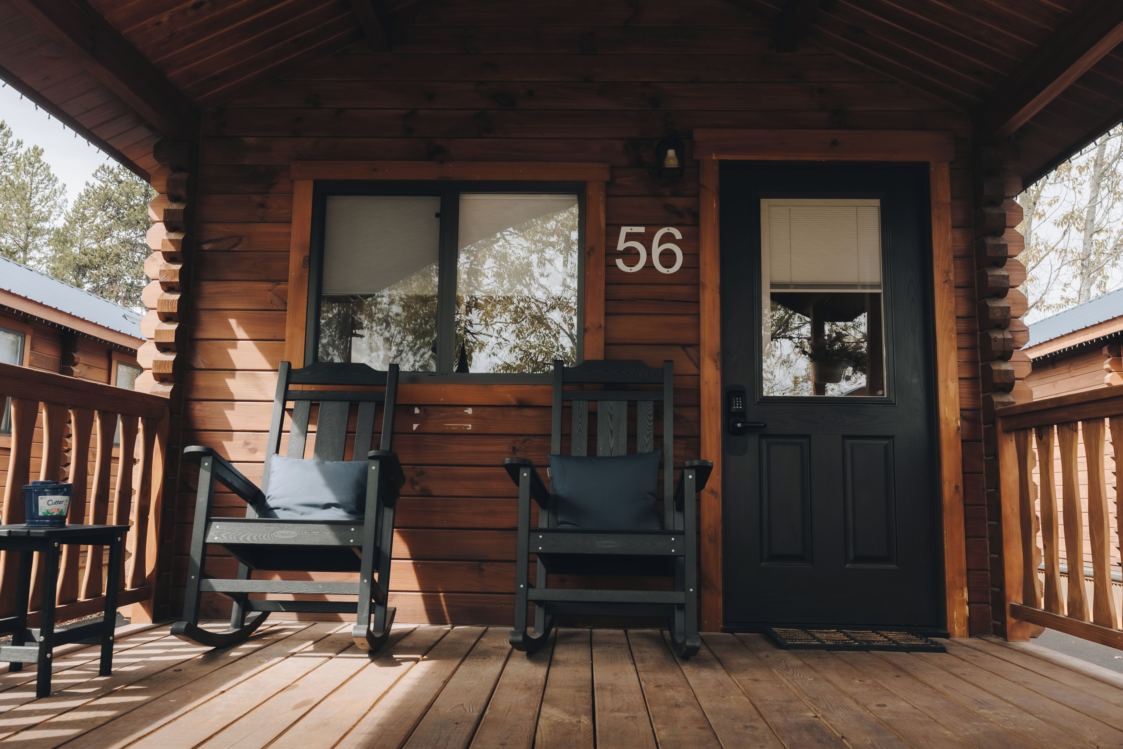 Eine Holzhütte mit Veranda, zwei Schaukelstühlen und einer Tür mit der Nummer 56.