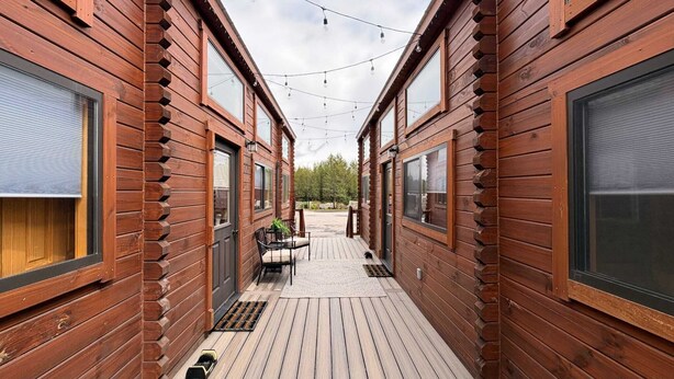 A narrow wooden corridor with a deck, outdoor seating, and string lights. - Blue Buffalo Resort (Island Park)