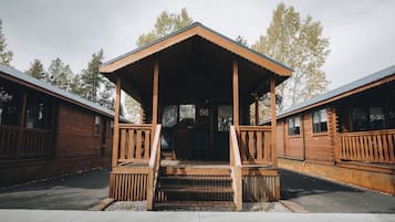 A wooden lodge with a porch and steps leading to the entrance, numbered 56.