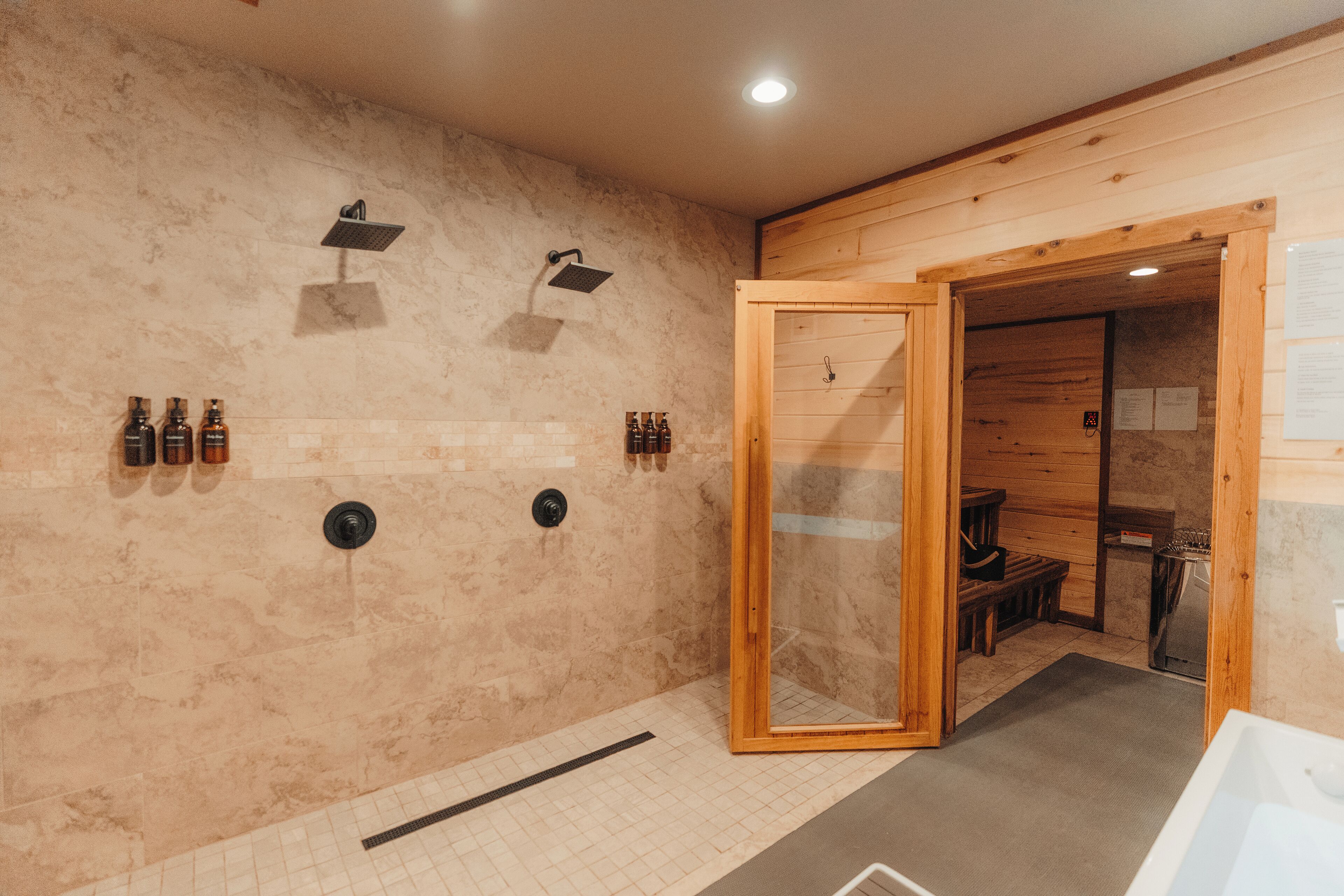 A spa room with a wooden floor, a glass shower enclosure, and a wooden bench.