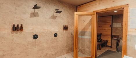 A spa room with a wooden floor, a glass shower enclosure, and a wooden bench.